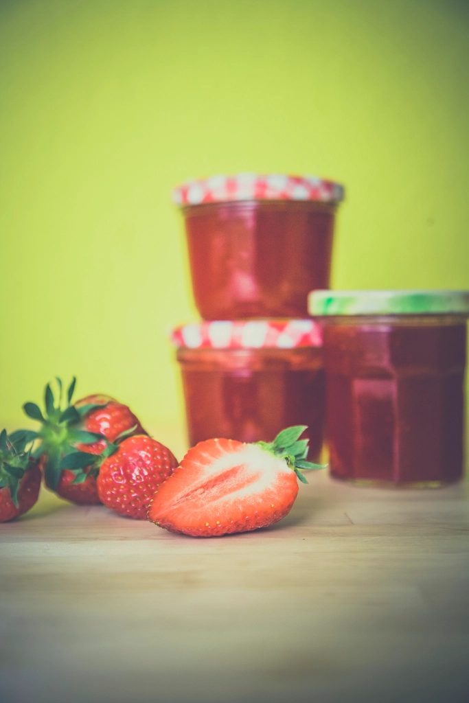 Jars of Jamtastic jam cooling on a farmhouse kitchen table
