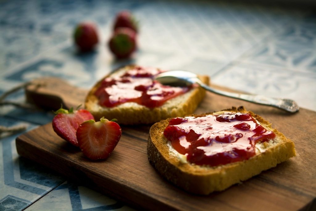 Two slices of toast spread thick with red jam